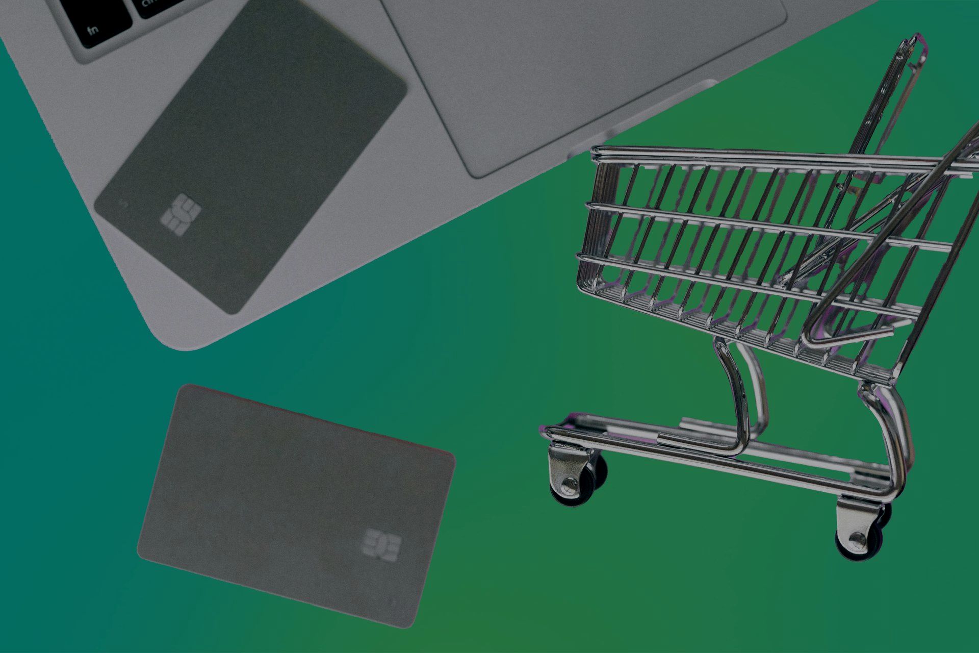 A credit card and laptop next to a shopping cart, representing online commerce